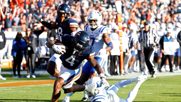 Nov 18, 2023; Charlottesville, Virginia, USA; Virginia Cavaliers wide receiver Malik Washington (4) scores a touchdown as Duke Blue Devils safety Jaylen Stinson (2) chases during the first quarter at Scott Stadium. Mandatory Credit: Geoff Burke-USA TODAY Sports  